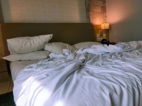 A rumpled, slept-in bed in a hotel.
